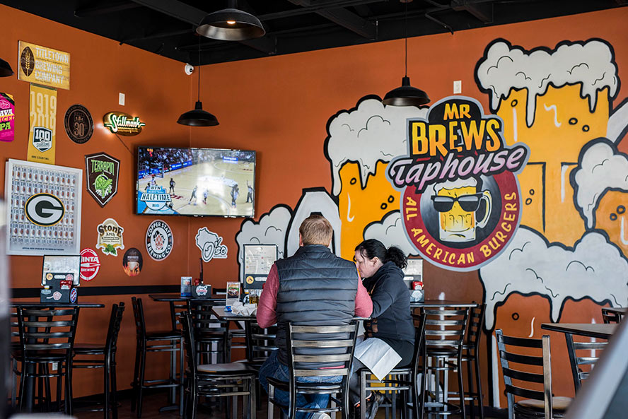 People dining inside the restaurant with artwork on the wall